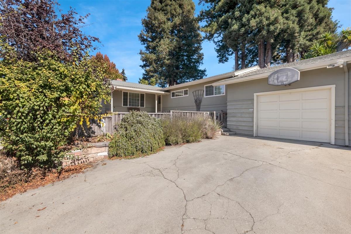 front view of house with a yard and trees all around