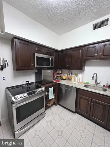 a kitchen with granite countertop a stove top oven sink and cabinets