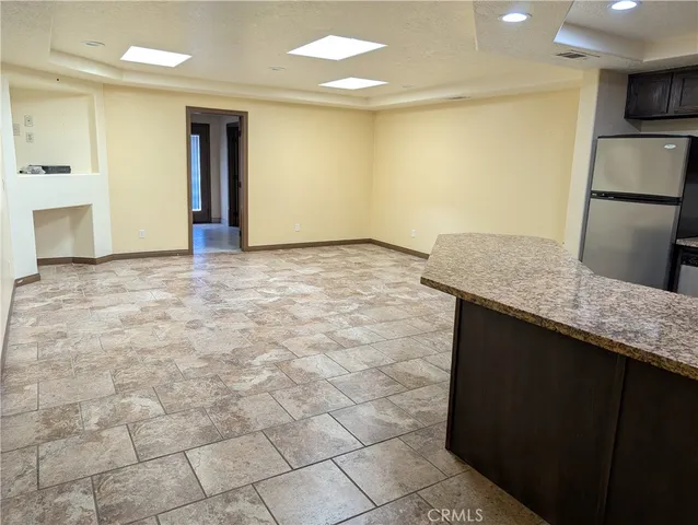 a kitchen with kitchen island granite countertop a sink refrigerator and cabinets