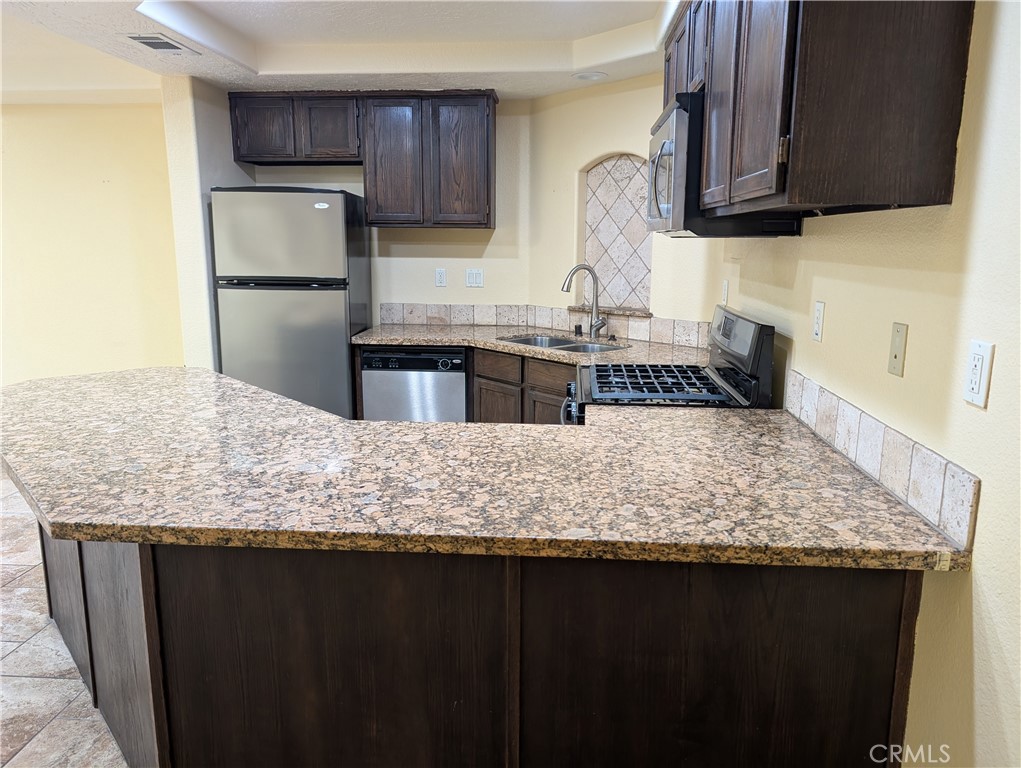 27160 Vista Road, Unit 8 Helendale, CA 92342 - Photo 9 of 12 a kitchen with kitchen island granite countertop a sink refrigerator and cabinets