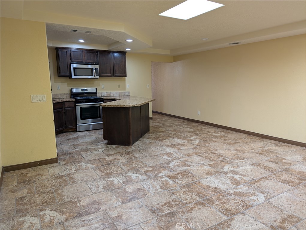 27160 Vista Road, Unit 8 Helendale, CA 92342 - Photo 10 of 12 a kitchen with granite countertop a stove a sink and a microwave