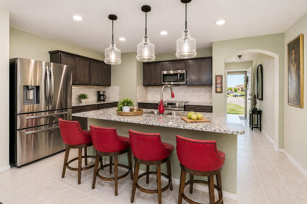 910 Community Way Royse City, TX 75189 - Photo 4 of 27 a kitchen with stainless steel appliances kitchen island granite countertop a dining table chairs sink refrigerator and microwave
