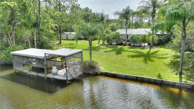 a view of a lake with lawn chairs and a big yard