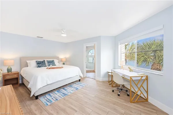a bedroom with a bed a table and chair with wooden floor