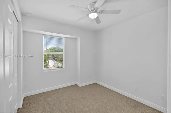 an empty room with a window and a fan