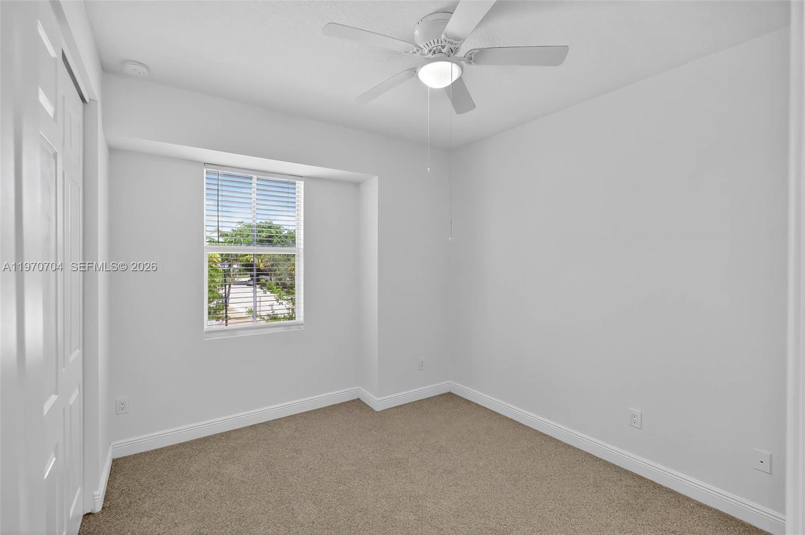 7651 North Pine Island Road Tamarac, FL 33321 - Photo 5 of 9 an empty room with a window and a fan