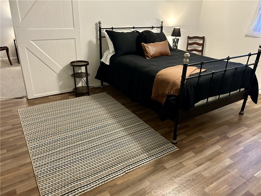 28639 Rostrata Avenue Lake Elsinore, CA 92532 - Photo 30 of 43 a bedroom with a bed and wooden floor