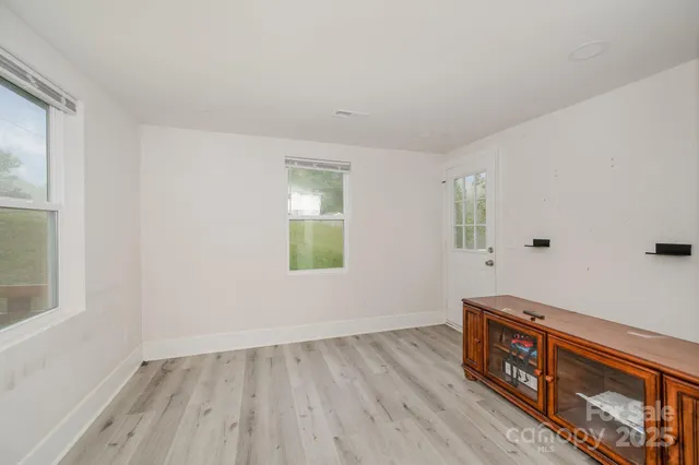a view of an empty room with window and wooden floor