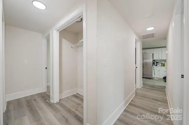 a view of a hallway with wooden floor and a bathroom