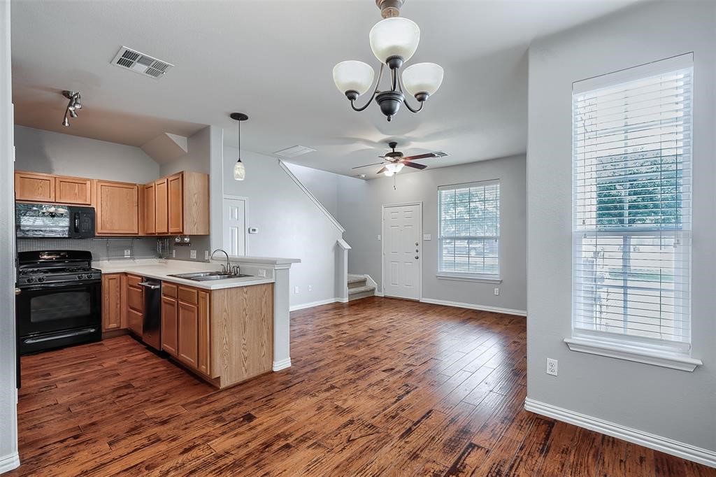a large kitchen with hardwood floor a sink cabinets and stainless steel appliances