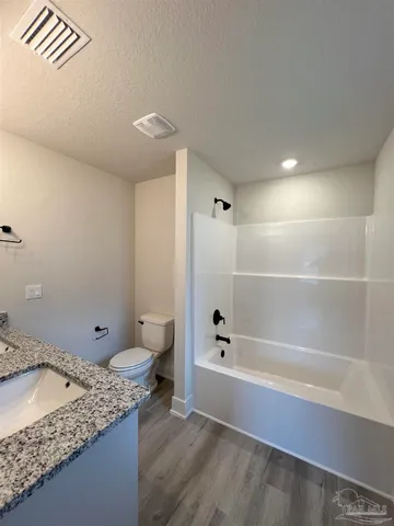 a bathroom with a granite countertop sink a toilet and shower