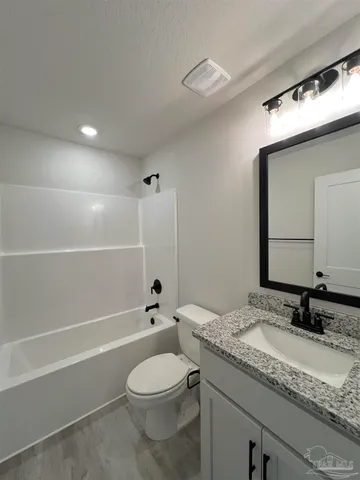 a bathroom with a granite countertop sink a toilet and shower