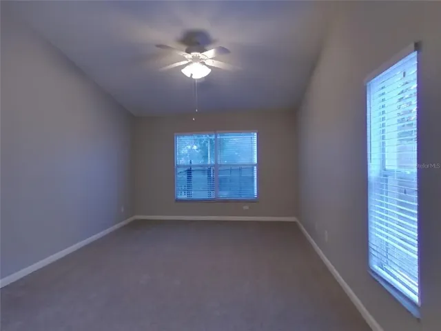 en empty room with windows and chandelier fan