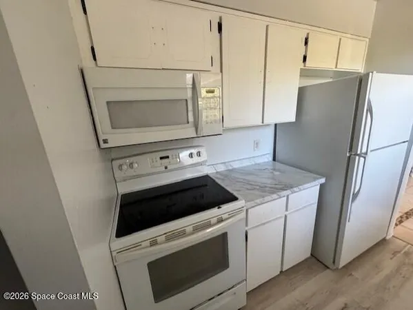a kitchen with white cabinets and white appliances