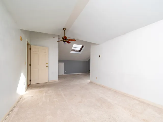 an empty room with chandelier fan and windows