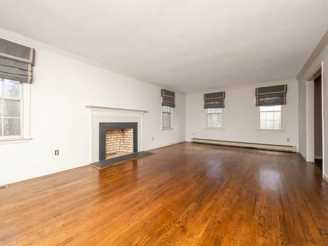 a view of empty room with wooden floor and fireplace