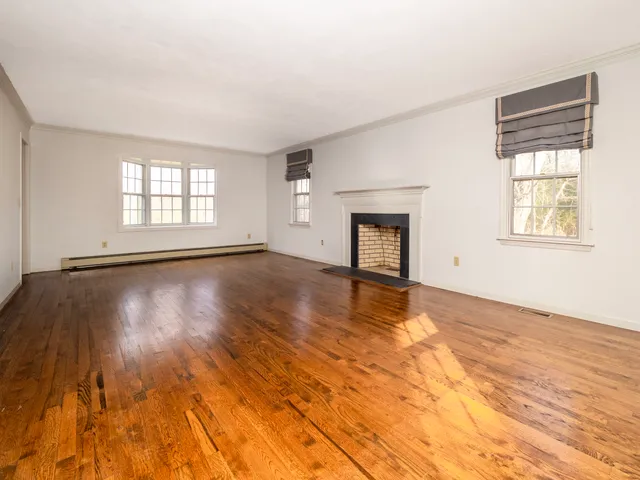 an empty room with windows and fireplace