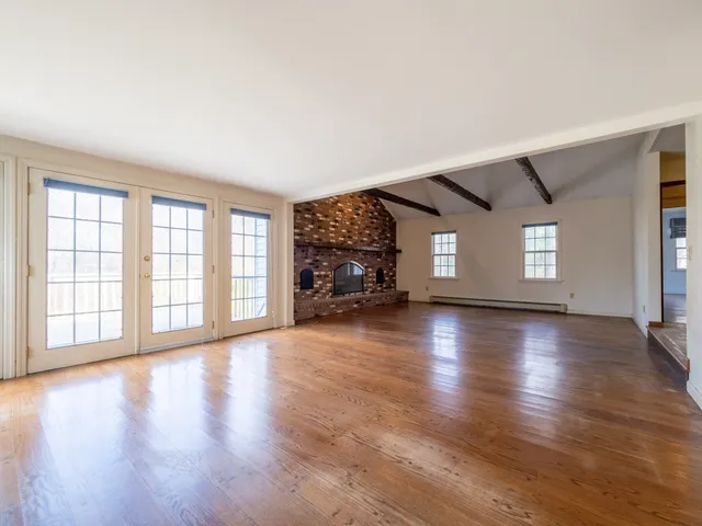 a view of an empty room with window and wooden floor
