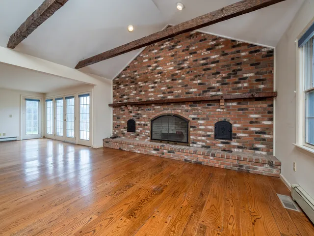 a view of empty room with wooden floor and fireplace