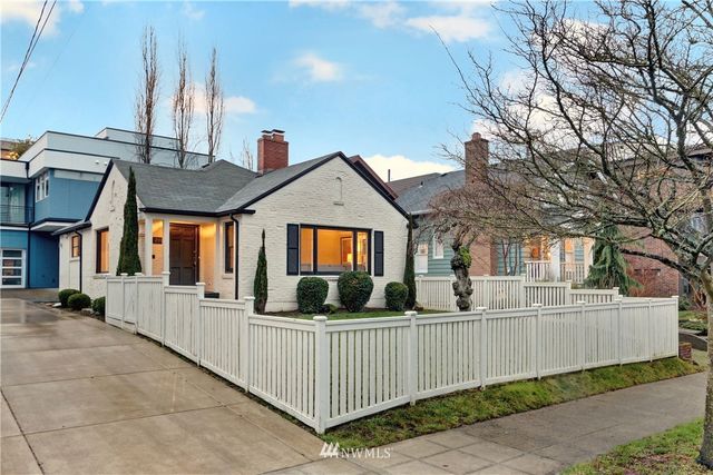 a front view of a house with large trees and furniture