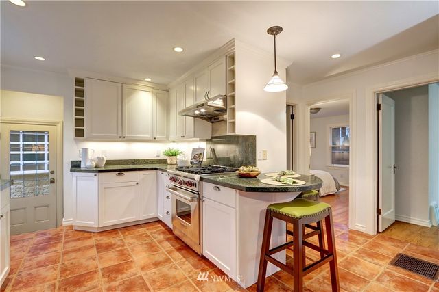 a kitchen with stainless steel appliances granite countertop a stove top oven a sink dishwasher and a refrigerator