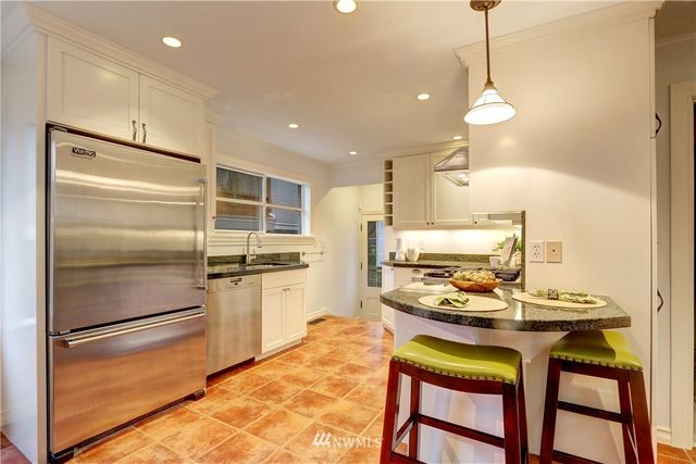a kitchen with kitchen island a stove a refrigerator and a dining table with wooden floor