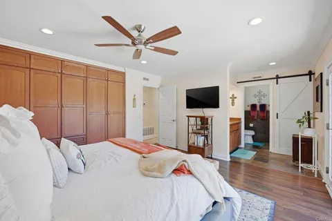 a bedroom with a bed a flat tv screen and a chandelier