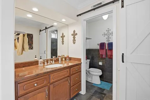 a bathroom with a granite countertop toilet sink and mirror
