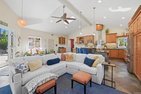 a living room with furniture kitchen view and a chandelier
