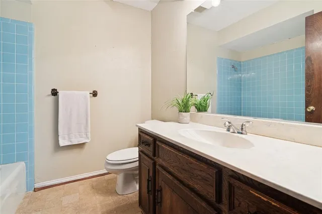 a bathroom with a granite countertop sink a toilet and a mirror