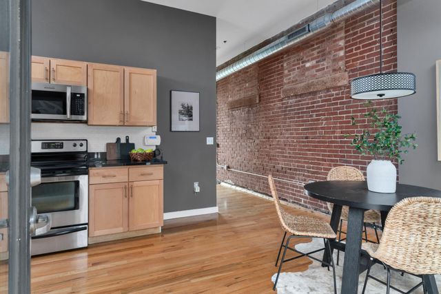 a kitchen with stainless steel appliances granite countertop a stove a sink dishwasher a microwave oven and a dining table with wooden floor