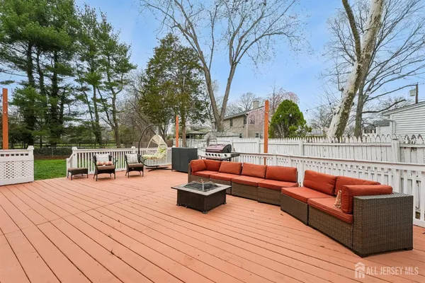 a roof deck with couches and potted plants with wooden floor and fence