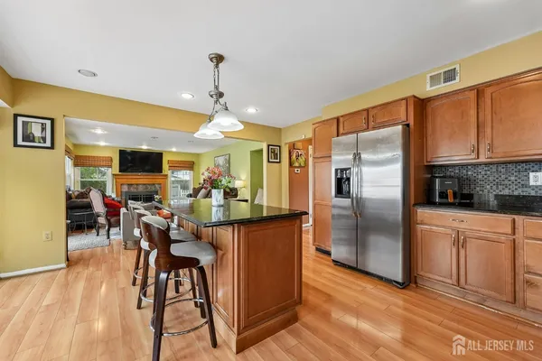 a kitchen with stainless steel appliances kitchen island granite countertop a refrigerator a stove a microwave oven a dining table and chairs with wooden floor