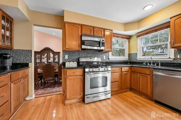 a kitchen with stainless steel appliances granite countertop a stove a sink and a microwave