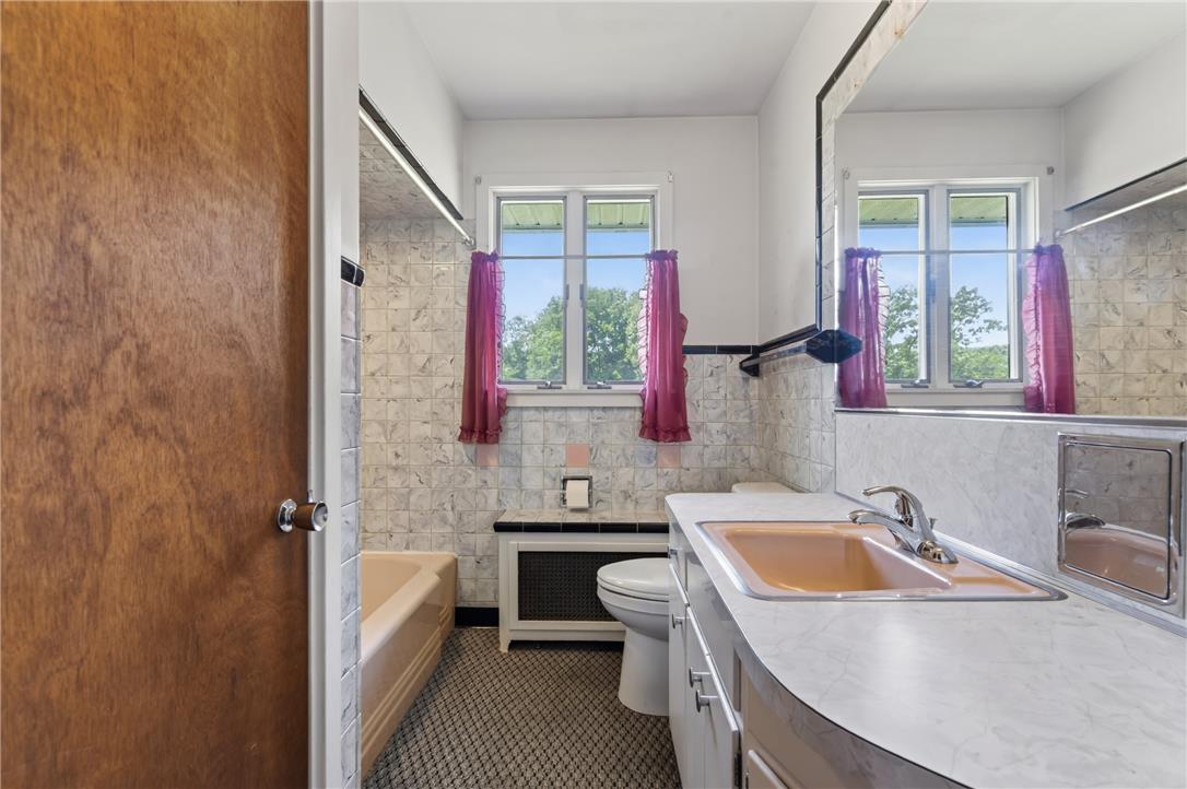 51 Reynolds Road Tamaqua, PA 18252 - Photo 36 of 71 A classic tiled bathroom features a window offering a lush green outdoor vista, enhancing the bright, functional space.