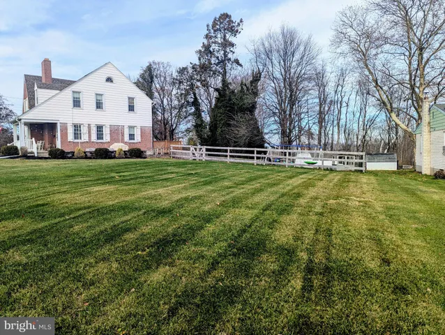 a view of a house with a big yard and large trees