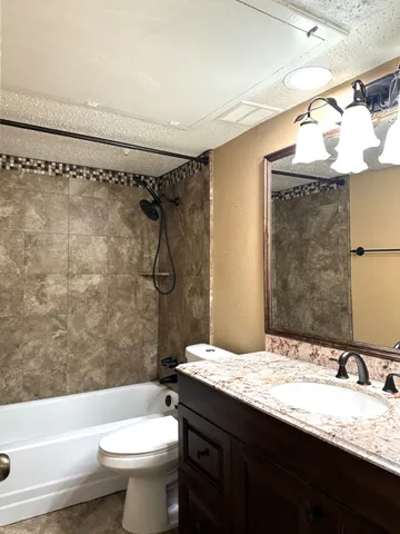 a bathroom with a granite countertop sink toilet and shower