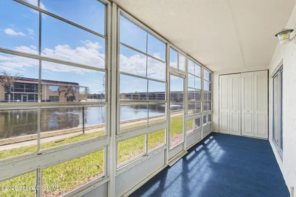 a view of an empty room with wooden floor and windows