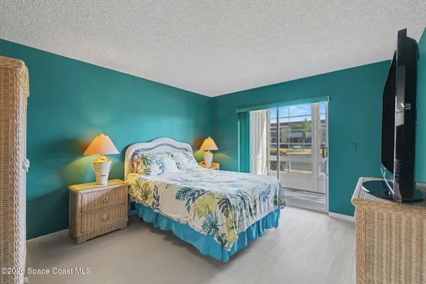 a bedroom with a bed and a flat tv screen on dresser