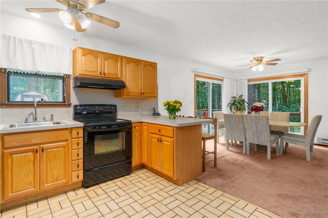 222 Powder Horn Road Henryville, PA 18332 - Photo 9 of 25 A warm kitchen and dining space with rich wooden cabinetry and tile flooring.
