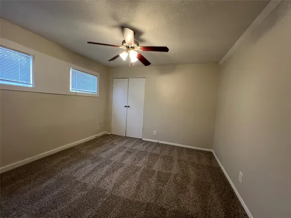 an empty room with a window and a fan