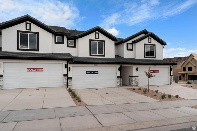 Contemporary multi-unit residence featuring white stucco siding with dark trim accents, multiple attached garages, stone facade detailing, and a black shingle roof