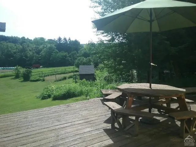 a backyard of a house with table and chairs under an umbrella