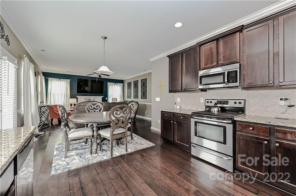 10311 Atkins Ridge Drive Charlotte, NC 28213 - Photo 5 of 18 a kitchen with stainless steel appliances granite countertop a stove top oven a sink dishwasher a dining table and chairs with wooden floor
