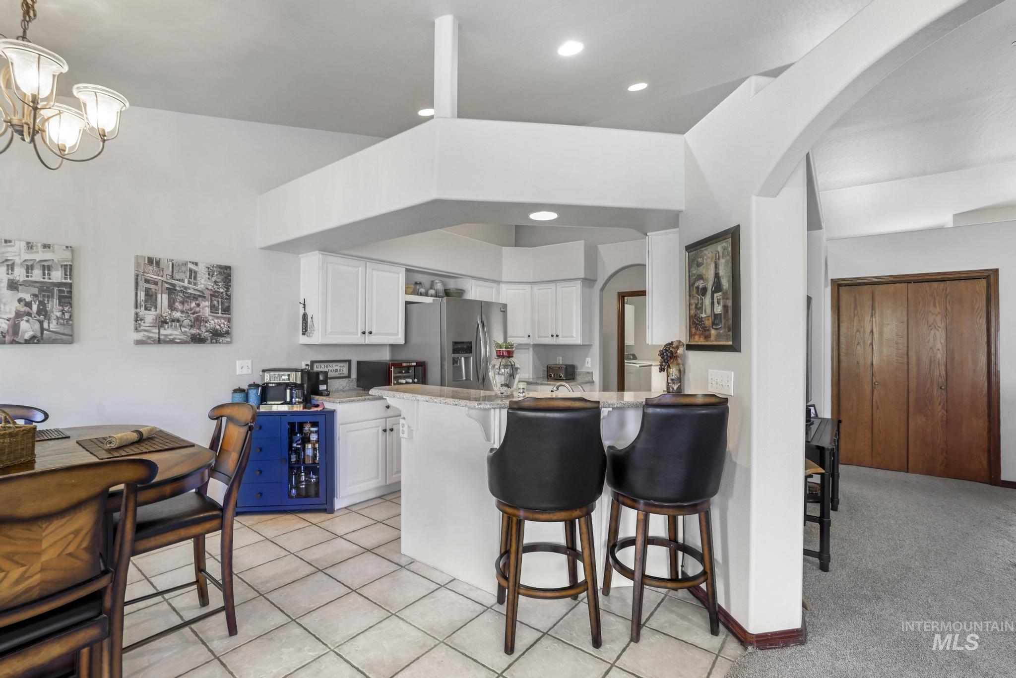 1558 Brookside Loop Twin Falls, ID 83301 - Photo 12 of 47 Kitchen featuring white cabinetry, light-toned tile flooring, stainless steel appliances, and a breakfast bar with stone-finish countertops