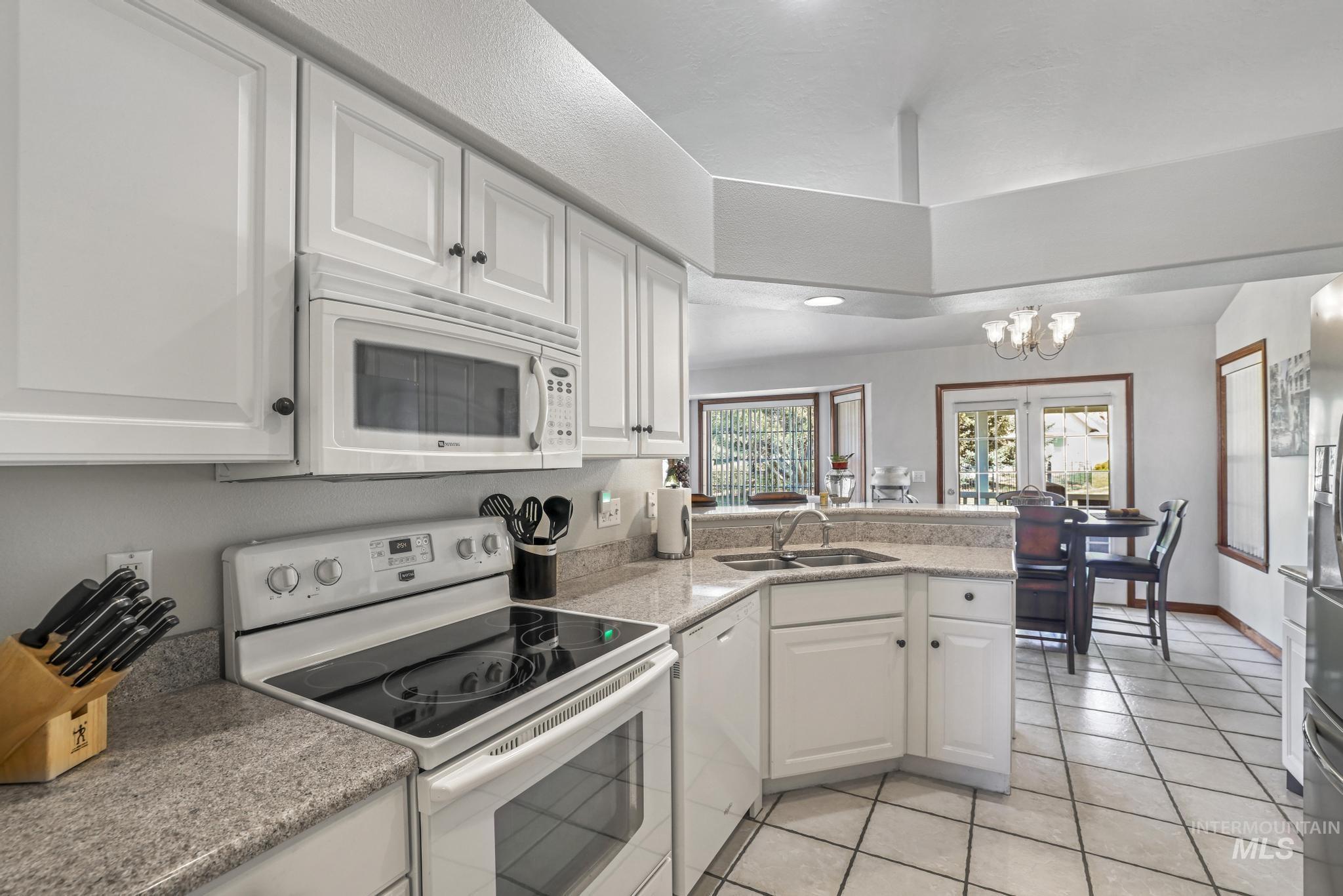 1558 Brookside Loop Twin Falls, ID 83301 - Photo 13 of 47 Kitchen featuring white cabinetry, light-toned countertops, tile flooring, and an integrated microwave