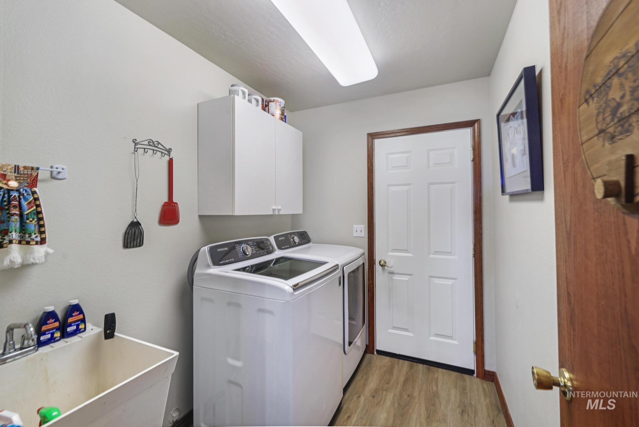 1558 Brookside Loop Twin Falls, ID 83301 - Photo 16 of 47 Dedicated utility space featuring wood-finish flooring, a utility sink, and wall-mounted cabinetry