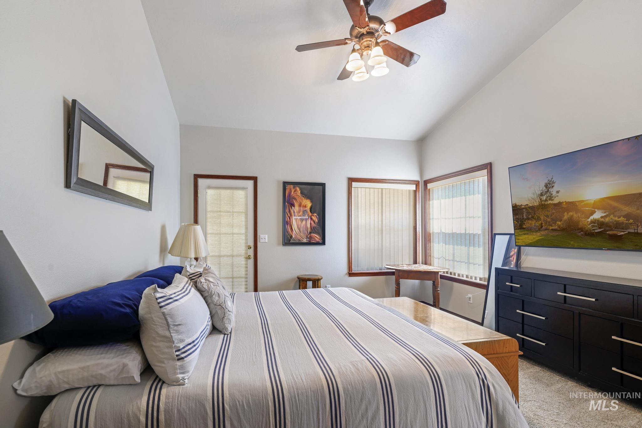 1558 Brookside Loop Twin Falls, ID 83301 - Photo 17 of 47 Vaulted ceiling bedroom featuring a ceiling fan, a glass-paned exterior door, and two windows with blinds