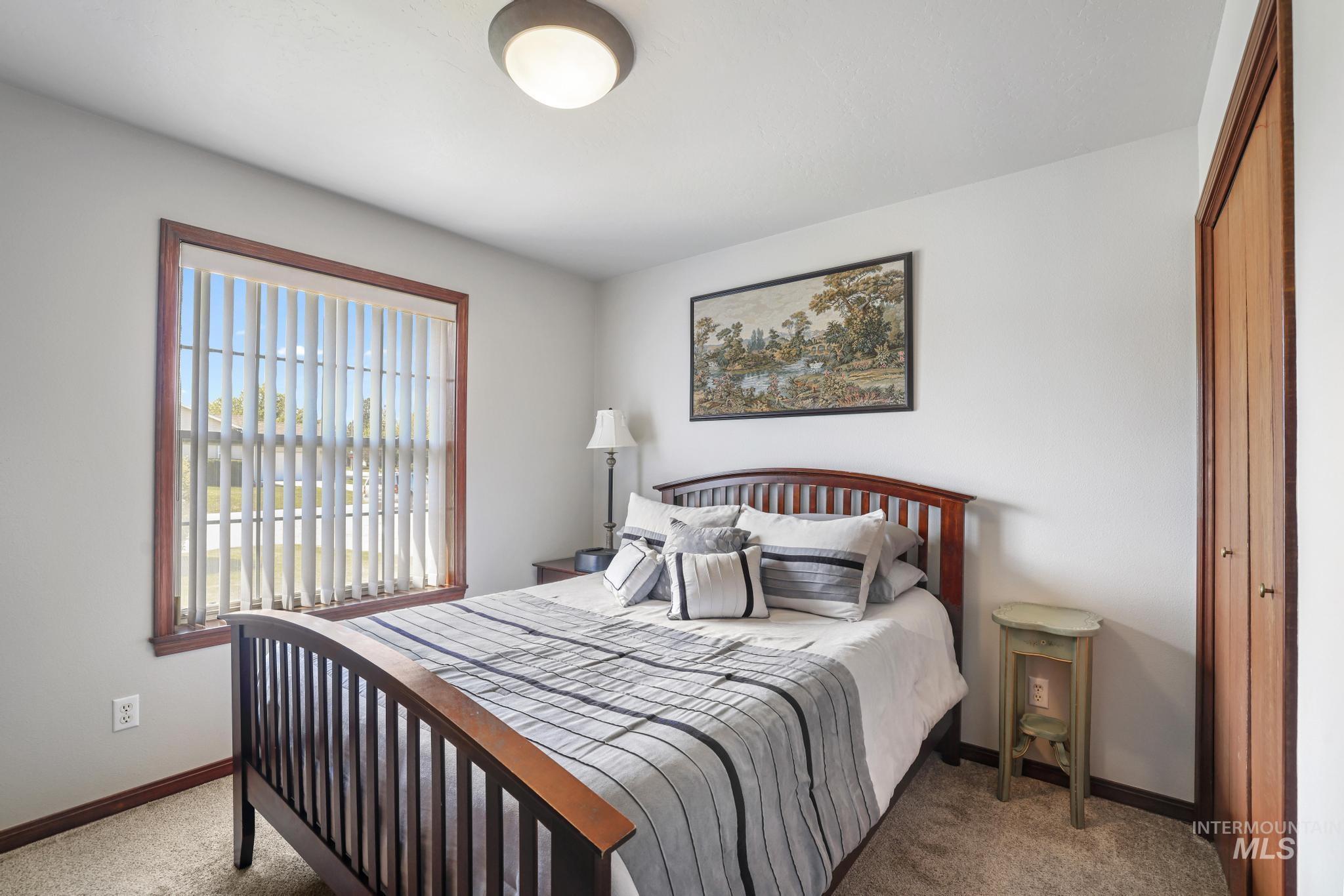 1558 Brookside Loop Twin Falls, ID 83301 - Photo 23 of 47 Bright bedroom featuring a large window with vertical blinds, light neutral wall paint, and a built-in closet with wood bi-fold doors