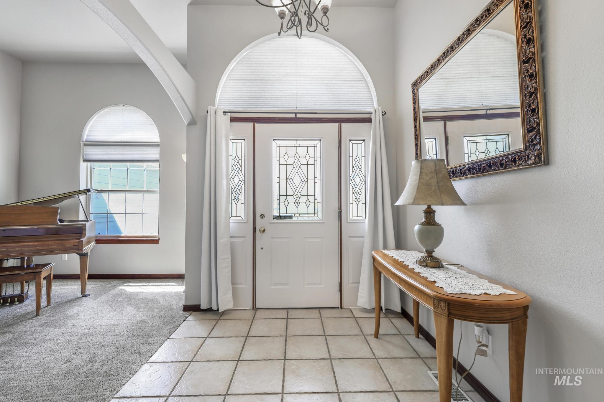 1558 Brookside Loop Twin Falls, ID 83301 - Photo 3 of 47 Entryway featuring a decorative front door with transom and sidelights, a tiled floor, arched architectural elements, and a carpeted room beyond